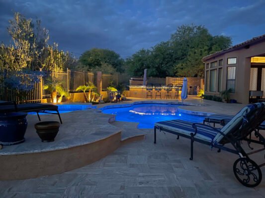 A desert landscaped yard in Arizona featuring a travertine pool deck.